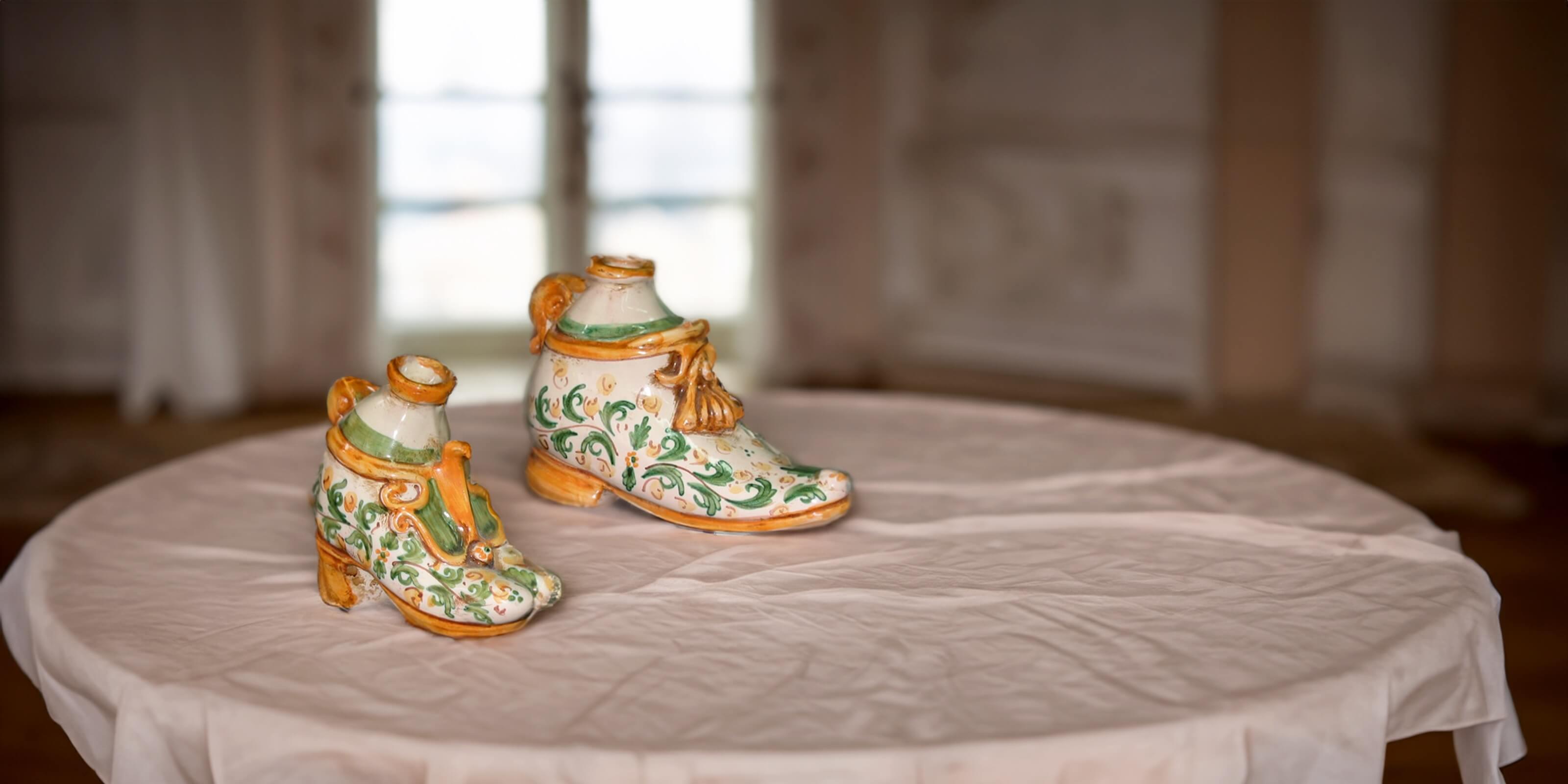 Scaldamani ceramiche Caltagirone Sofia a forma di stivali decorati, fatti a mano su tavolo.