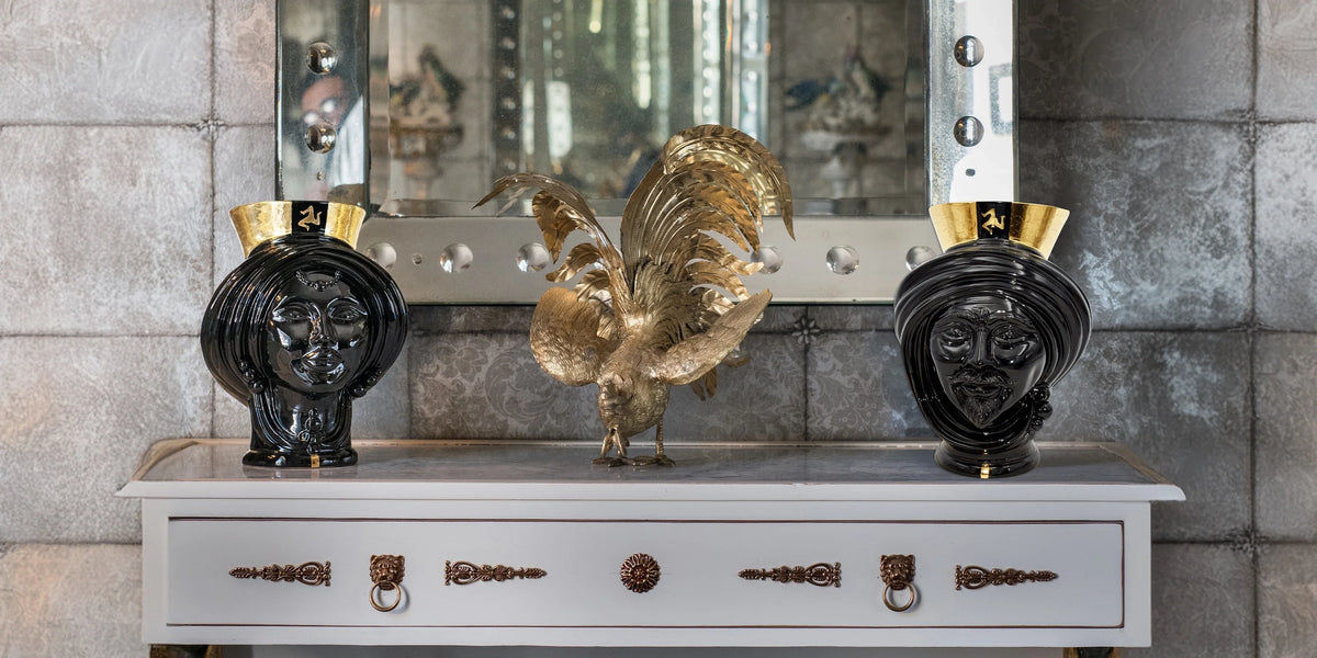 Teste di moro neri con dettagli oro, ceramiche Caltagirone fatti a mano su mobile elegante.