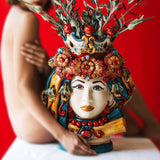 Testa di moro decorativa femmina in ceramica di Caltagirone fatta a mano con dettagli rossi, blu, gialli e fiori, sfondo rosso