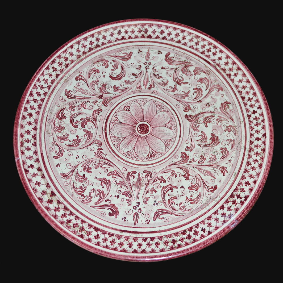Piatto in ceramica di Caltagirone fatta a mano con motivi floreali rossi e decori tradizionali
